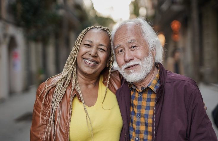 Happy multiracial senior couple smiling on camera outdoor